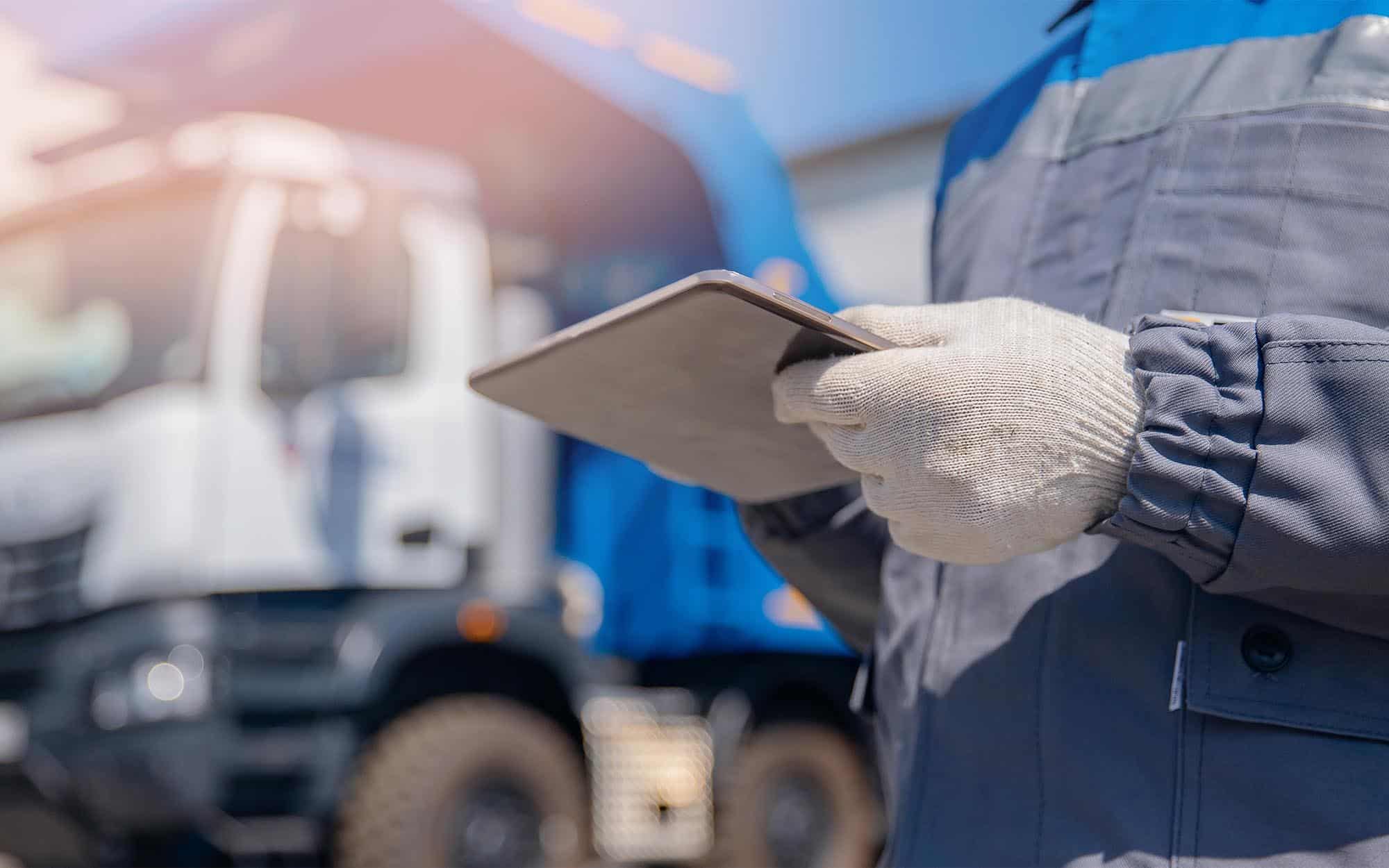 Worker checking tablet infront of trucks