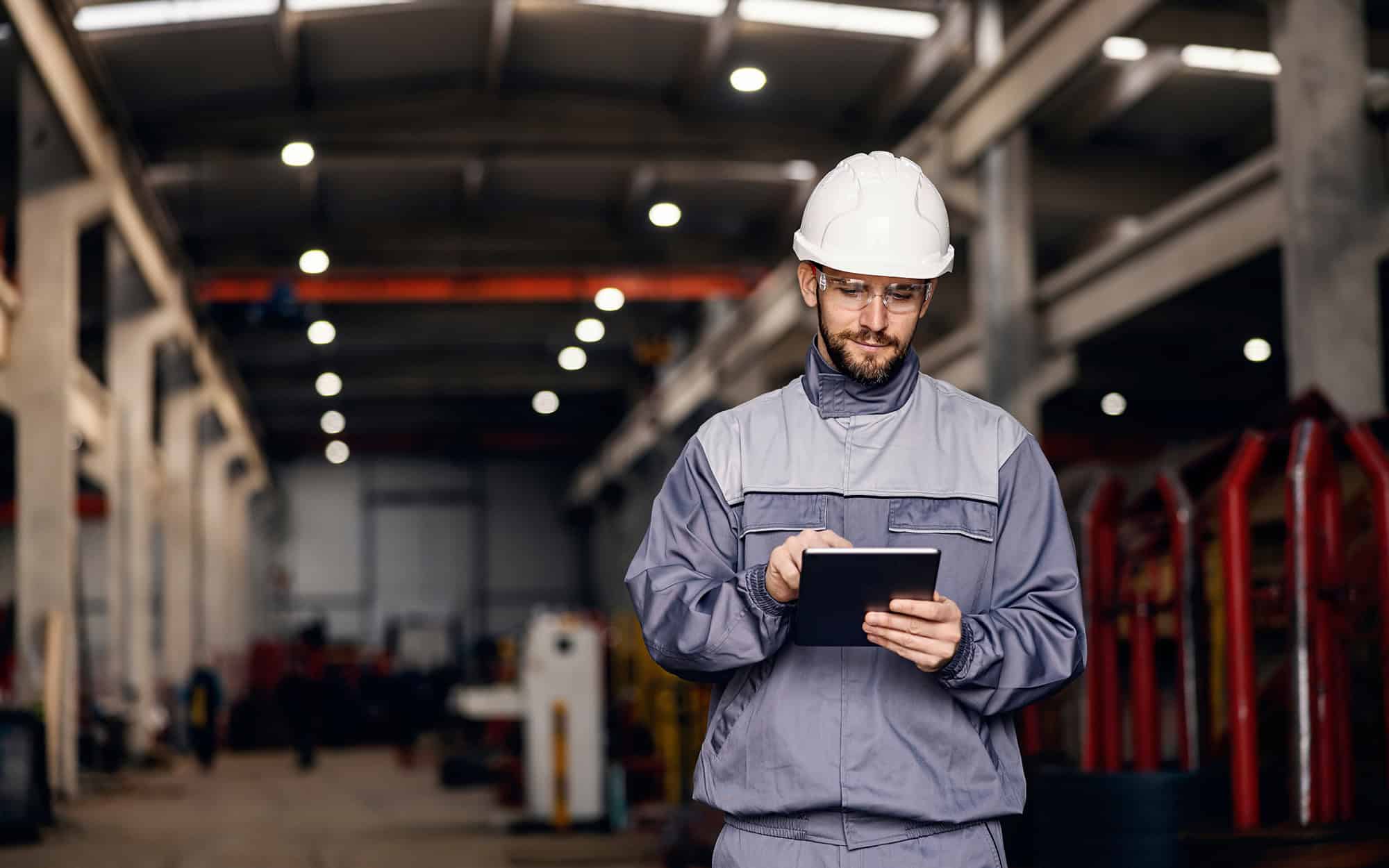 Focused heavy industry worker uses tablet in facility