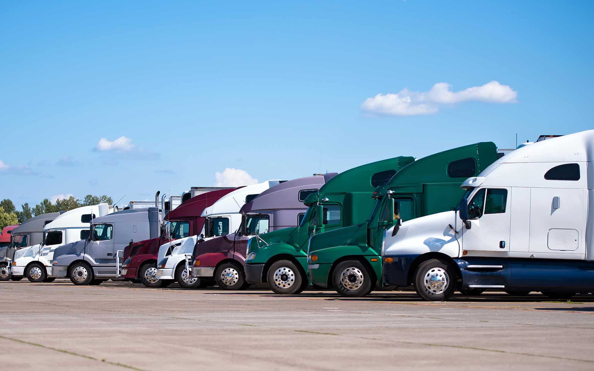 Side view of the fronts of many semitrucks lined up