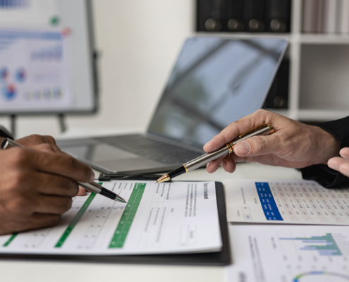 Side view of two people filling out financial doucments at desk