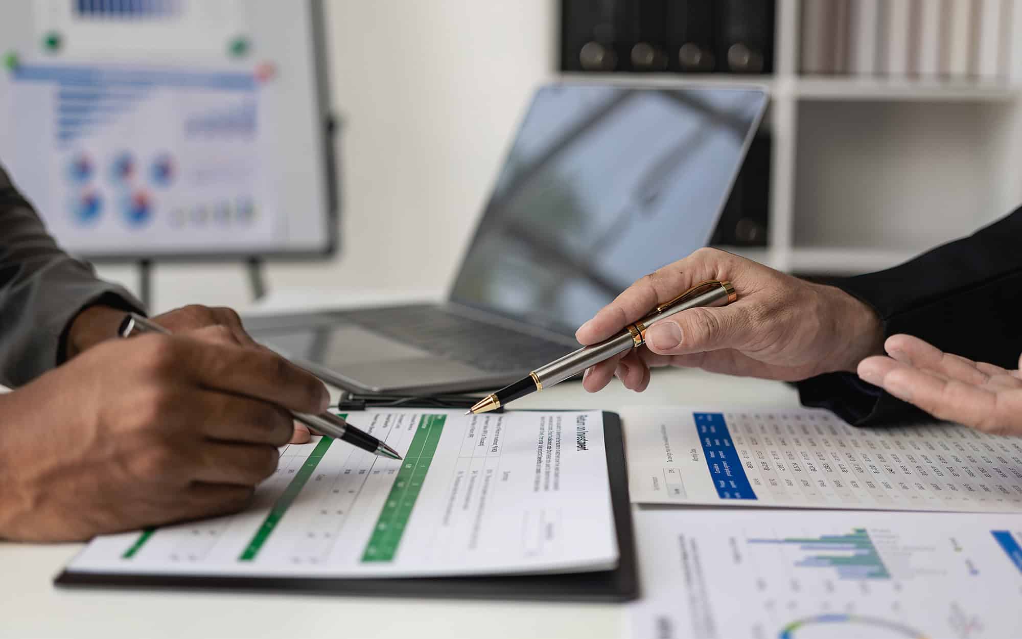 Side view of two people filling out financial doucments at desk