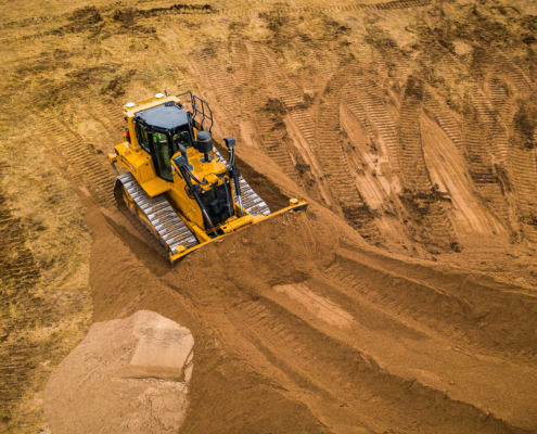 A bull dozer pushes sand into a large pile