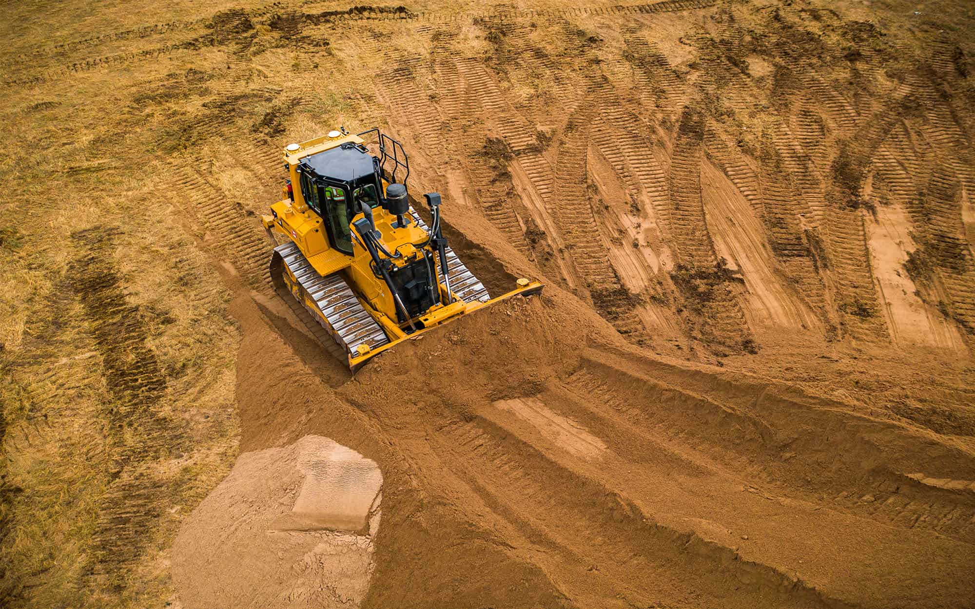 A bull dozer pushes sand into a large pile