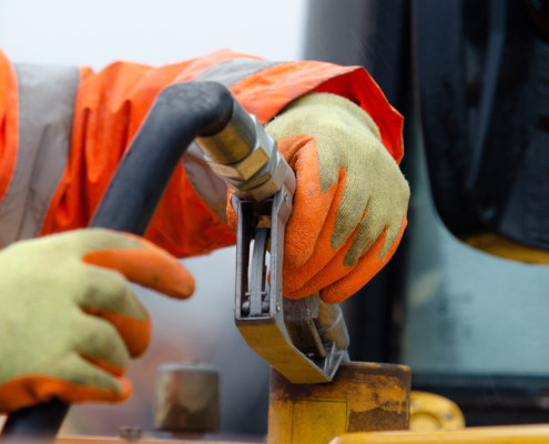 Construction worker in safety gloves filling excavator with diesel fuel on construction site