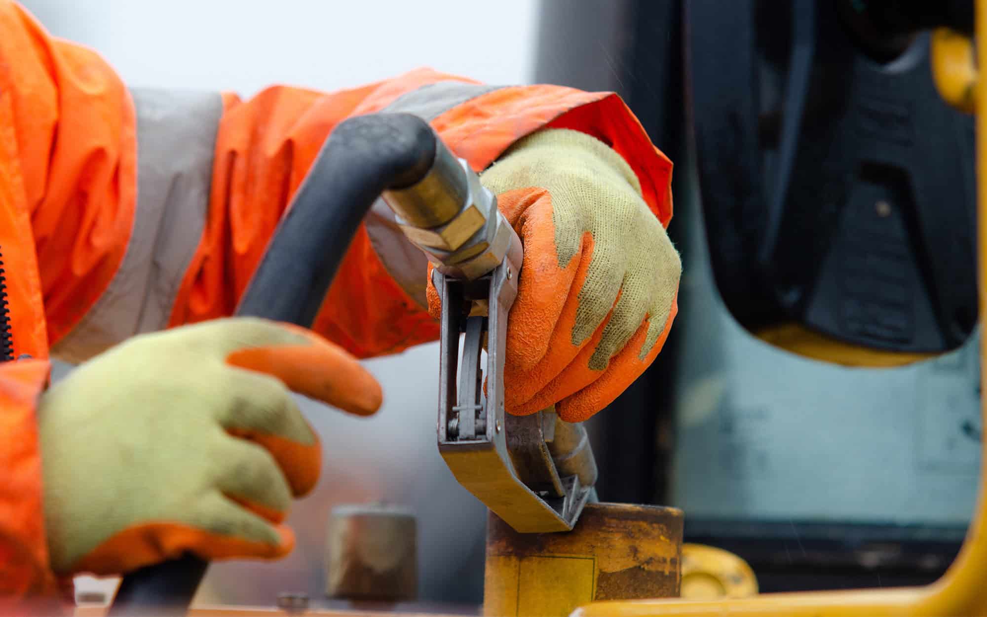 Construction worker in safety gloves filling excavator with diesel fuel on construction site